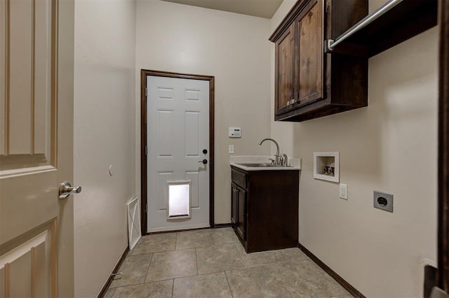 washroom with hookup for an electric dryer, washer hookup, a sink, baseboards, and cabinet space