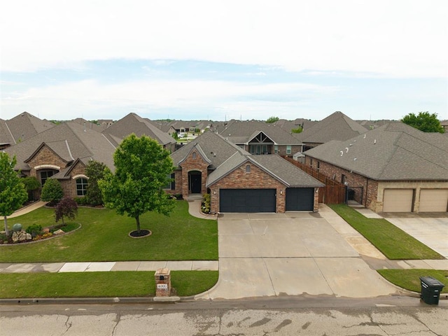 view of front of house with driveway, a residential view, stone siding, an attached garage, and a front lawn