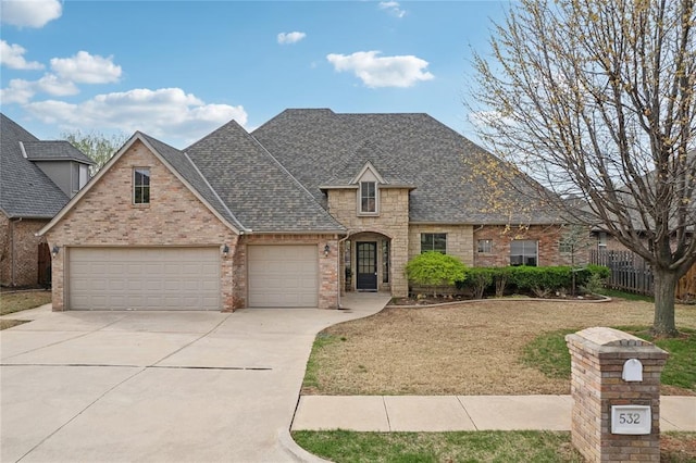 532 Conquistador Ct, Edmond, OK 73025 - french country style house with brick siding, fence, a shingled roof, driveway, and an attached garage
