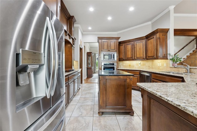 532 Conquistador Ct, Edmond, OK 73025 - kitchen with light stone counters, stainless steel appliances, ornamental molding, backsplash, and a center island