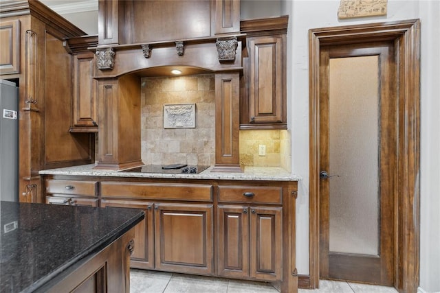 532 Conquistador Ct, Edmond, OK 73025 - kitchen featuring tasteful backsplash, light stone countertops, black electric stovetop, brown cabinetry, and light tile patterned floors
