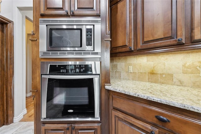532 Conquistador Ct, Edmond, OK 73025 - kitchen with baseboards, light stone countertops, stainless steel appliances, and decorative backsplash