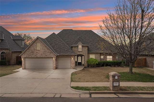 532 Conquistador Ct, Edmond, OK 73025 - french country home with driveway, stone siding, roof with shingles, a lawn, and a garage