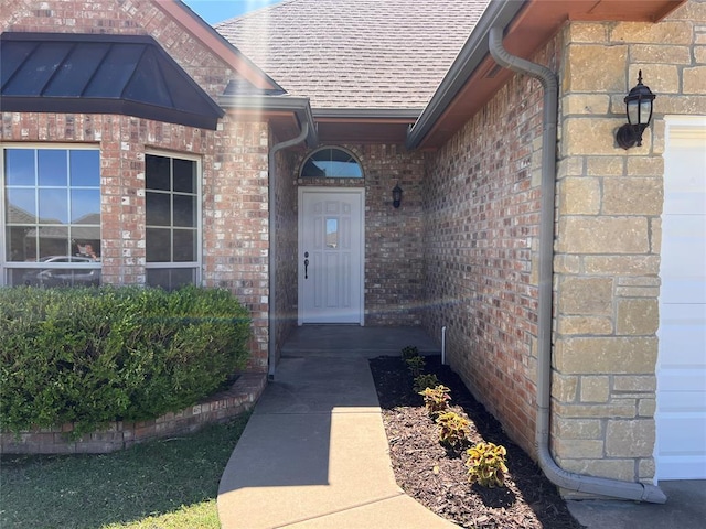 doorway to property featuring brick siding and a shingled roof