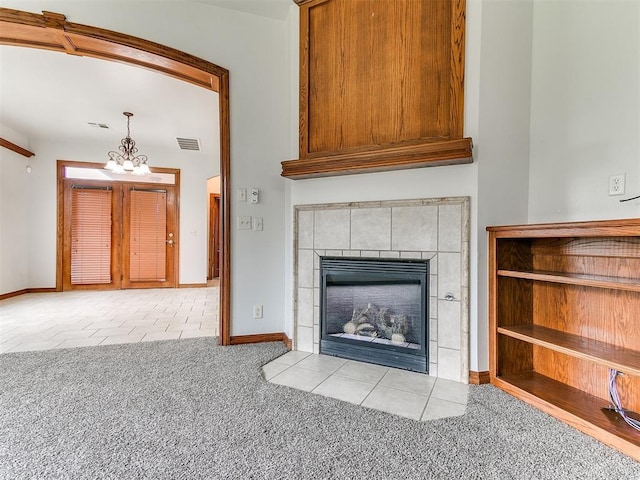 unfurnished living room featuring carpet flooring, a notable chandelier, tile patterned flooring, baseboards, and visible vents