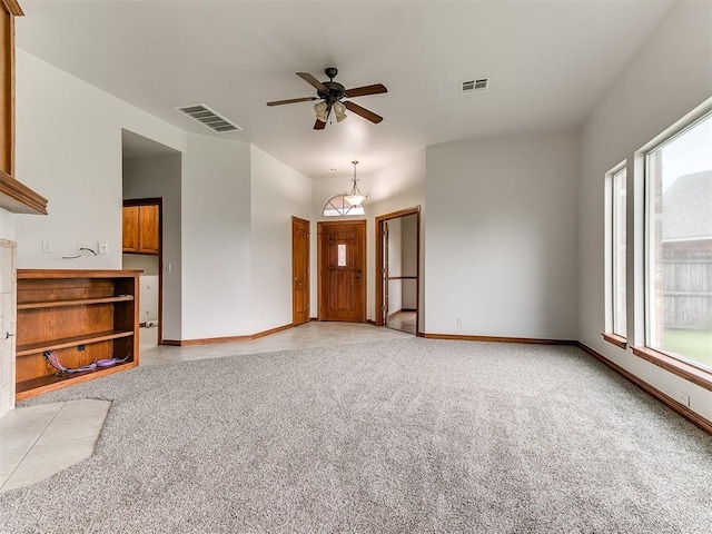 unfurnished living room with plenty of natural light, a ceiling fan, and visible vents