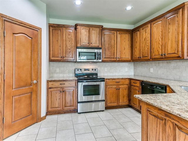 kitchen featuring light stone counters, stainless steel appliances, brown cabinets, and light tile patterned flooring