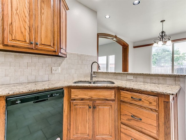 kitchen with a sink, black dishwasher, brown cabinets, and light stone countertops