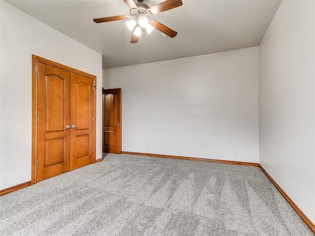 carpeted empty room featuring baseboards and a ceiling fan