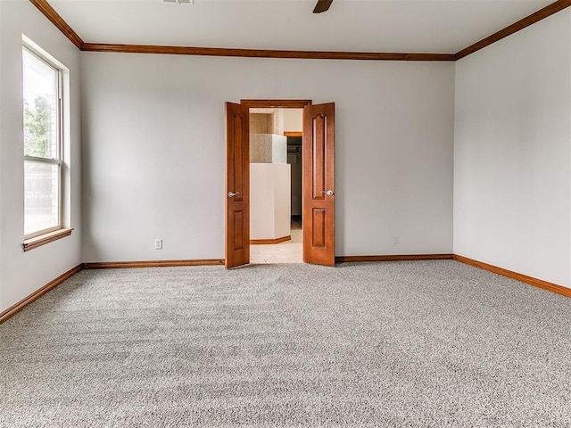 empty room with crown molding, baseboards, and light carpet