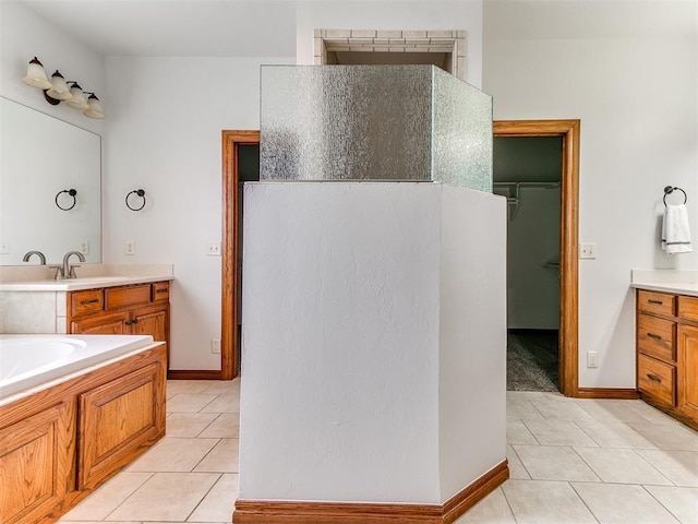 bathroom with baseboards, tile patterned flooring, vanity, and a bathtub