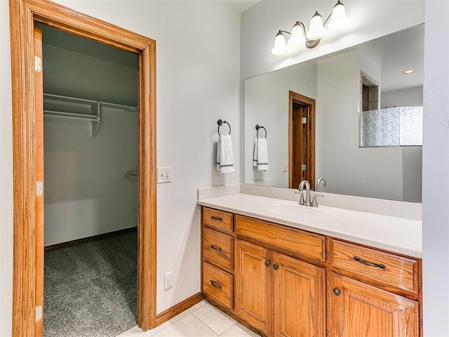 bathroom featuring vanity, baseboards, tile patterned floors, and a spacious closet
