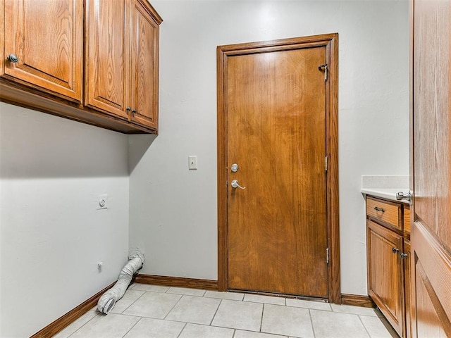 laundry room featuring light tile patterned floors, baseboards, electric dryer hookup, and cabinet space