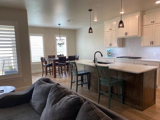 kitchen with light wood-type flooring, a center island with sink, open floor plan, and plenty of natural light