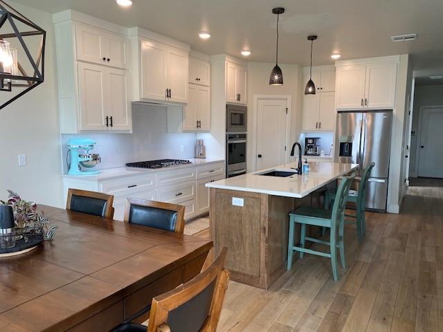 kitchen featuring white cabinets, light wood-style flooring, a sink, appliances with stainless steel finishes, and visible vents