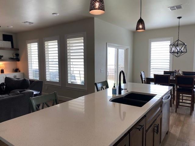 kitchen with open floor plan, light countertops, pendant lighting, and a sink