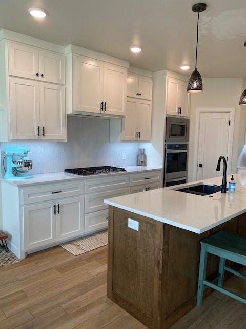 kitchen with white cabinetry, a sink, appliances with stainless steel finishes, and light countertops