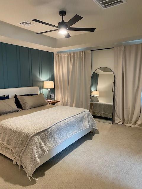 bedroom with visible vents, a ceiling fan, light carpet, and arched walkways