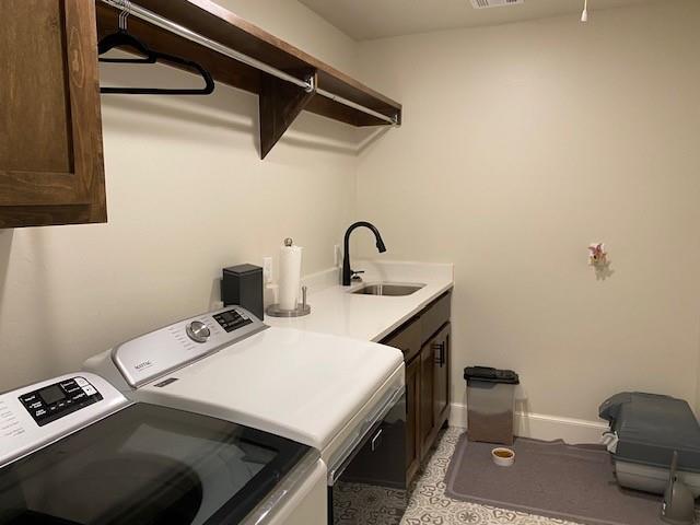 laundry room with washer and clothes dryer, cabinet space, baseboards, and a sink
