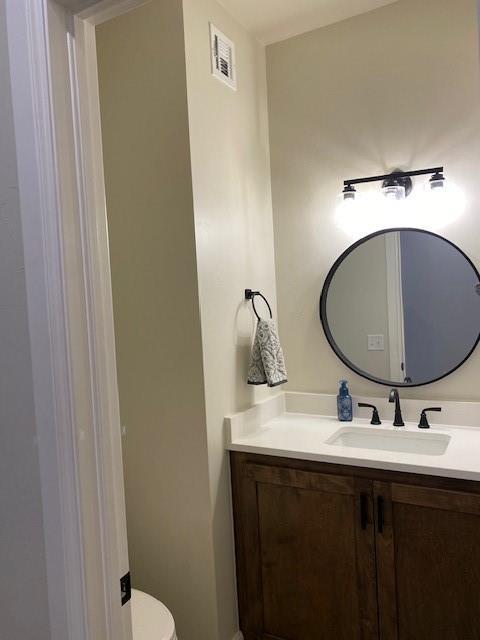 bathroom featuring toilet, visible vents, and vanity