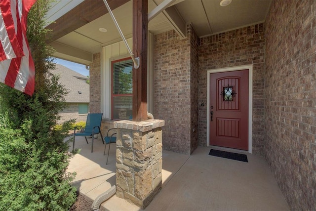 property entrance with a porch and brick siding