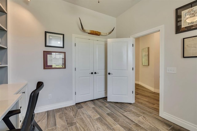 unfurnished office with baseboards and wood finished floors