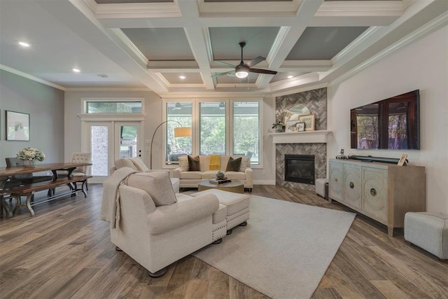 living area with a tiled fireplace, a ceiling fan, a healthy amount of sunlight, and beamed ceiling