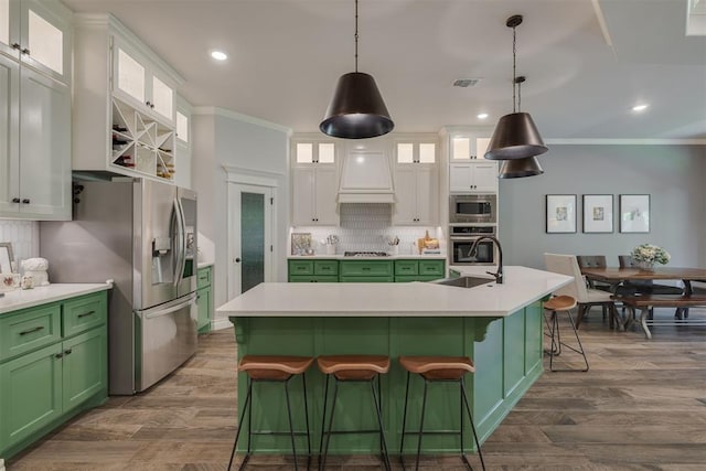 kitchen with appliances with stainless steel finishes, custom exhaust hood, a sink, and green cabinets