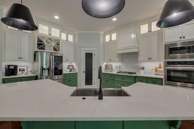 kitchen with stainless steel appliances, decorative backsplash, a sink, and green cabinets