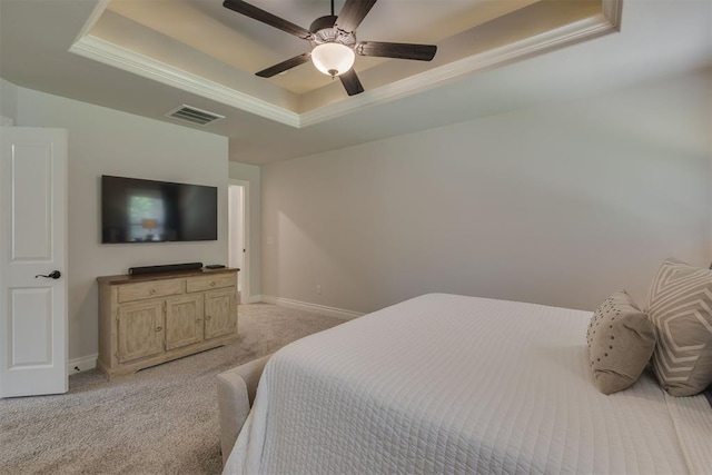 bedroom with light colored carpet, a raised ceiling, baseboards, visible vents, and ornamental molding