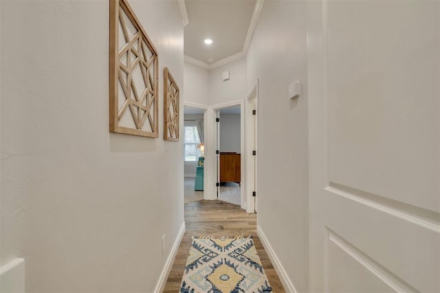 corridor featuring light wood-type flooring, ornamental molding, baseboards, and recessed lighting