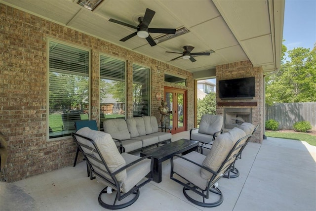 view of patio / terrace with a ceiling fan, an outdoor living space with a fireplace, fence, and french doors