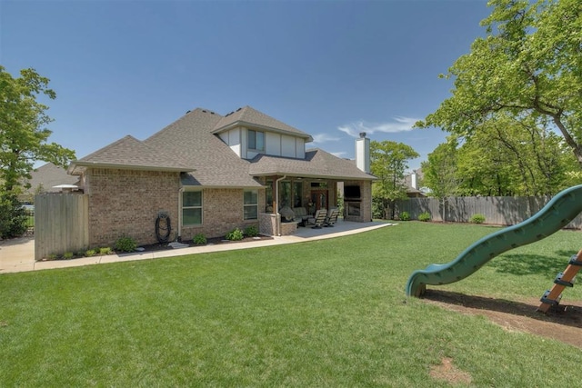 back of house featuring fence, roof with shingles, brick siding, a chimney, and a yard