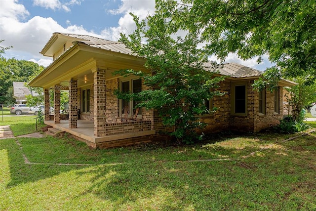 801 Lincoln St, Ryan, OK 73565 - view of property exterior featuring brick siding, a lawn, a porch, and metal roof