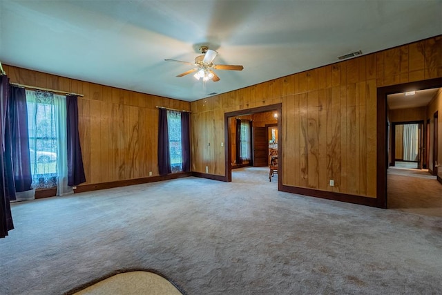 801 Lincoln St, Ryan, OK 73565 - carpeted spare room featuring ceiling fan, wood walls, and healthy amount of natural light