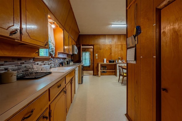 801 Lincoln St, Ryan, OK 73565 - kitchen featuring a sink, brown cabinets, tasteful backsplash, wooden walls, and light countertops