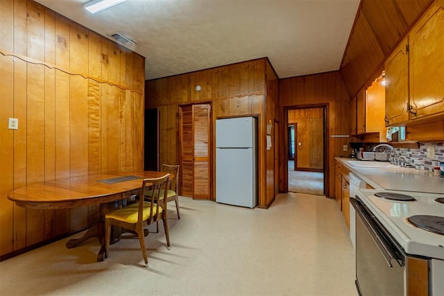 801 Lincoln St, Ryan, OK 73565 - kitchen featuring white appliances, wooden walls, brown cabinetry, a sink, and light countertops