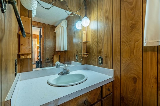801 Lincoln St, Ryan, OK 73565 - bathroom featuring wooden walls, vanity, and a textured ceiling
