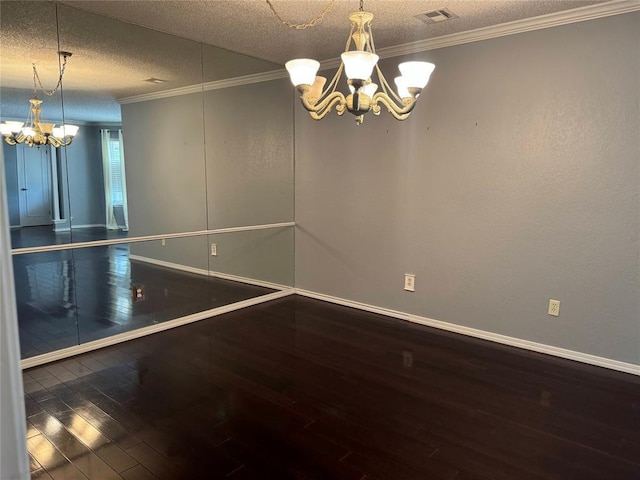 spare room with a textured ceiling, an inviting chandelier, hardwood / wood-style flooring, and visible vents
