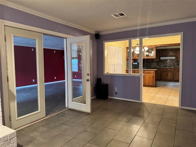 kitchen featuring light tile patterned floors, visible vents, backsplash, ornamental molding, and a textured ceiling