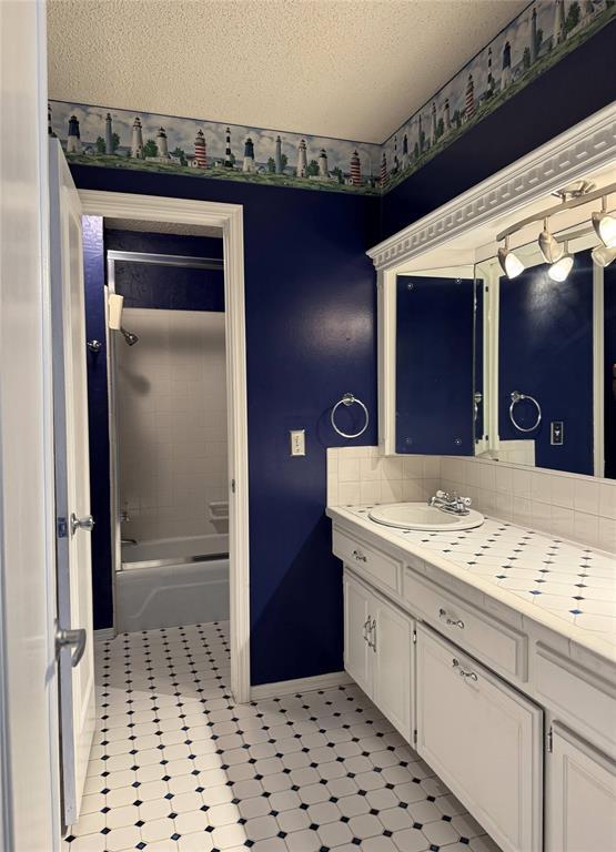 full bath with tasteful backsplash, a textured ceiling,  shower combination, and vanity