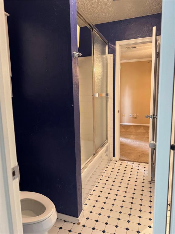 full bath featuring baseboards, visible vents, toilet, and a textured ceiling