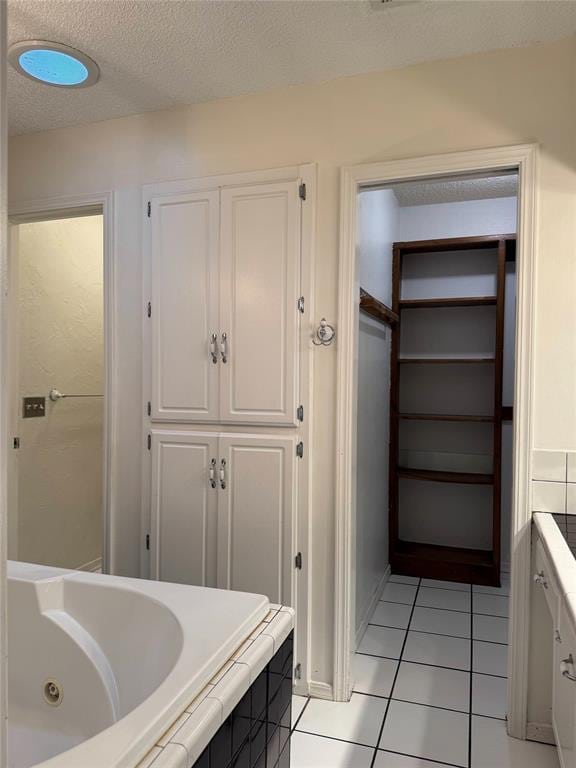 bathroom with tile patterned floors, a textured ceiling, and a jetted tub