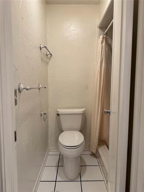 bathroom with toilet, tile patterned flooring, and a shower stall