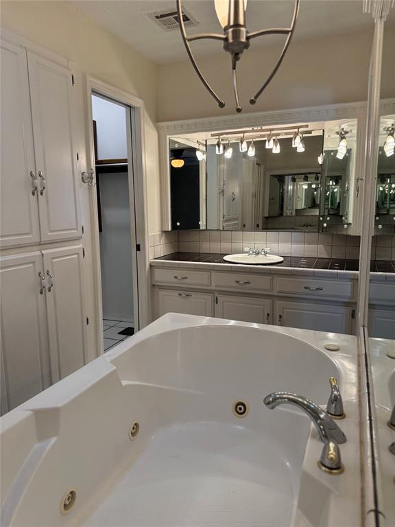 bathroom with visible vents, a whirlpool tub, and backsplash