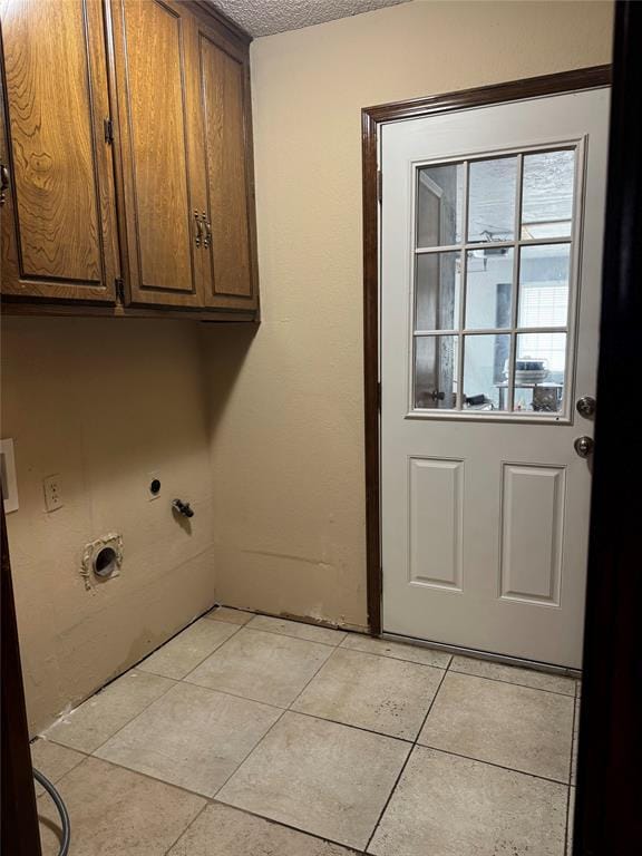 washroom with light tile patterned floors, washer hookup, a textured ceiling, electric dryer hookup, and cabinet space