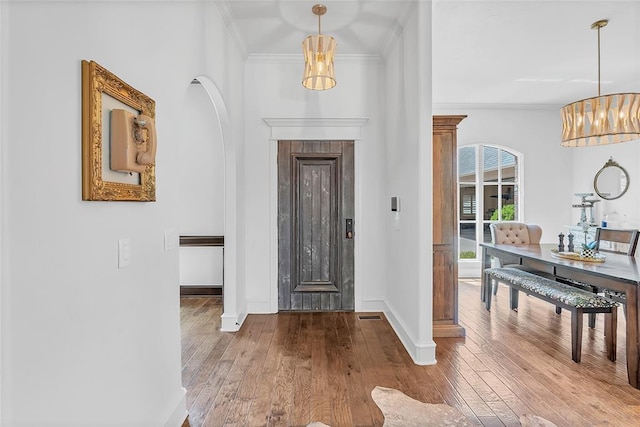 foyer entrance featuring baseboards, ornamental molding, and hardwood / wood-style floors