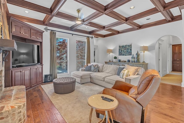 living area with arched walkways, a ceiling fan, hardwood / wood-style flooring, and coffered ceiling