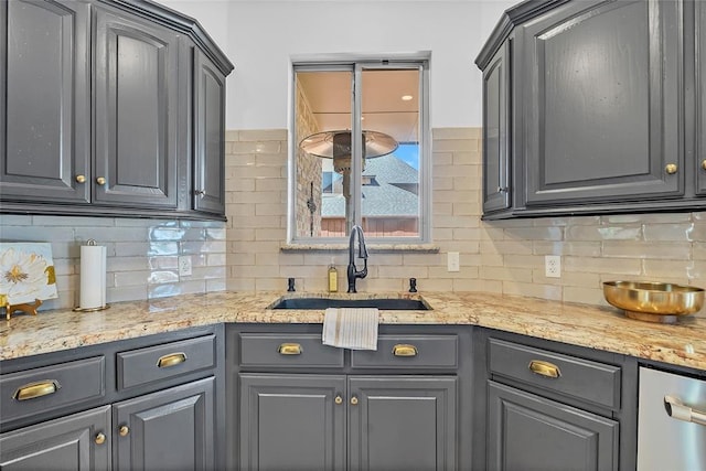 kitchen with gray cabinets, a sink, decorative backsplash, and stainless steel dishwasher