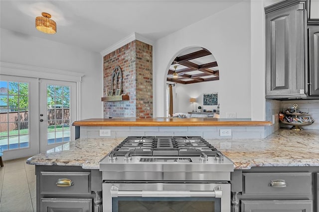 kitchen featuring decorative backsplash, beam ceiling, gray cabinetry, stainless steel gas range, and coffered ceiling